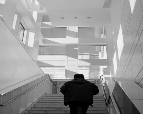 A person climbing stairs slowly in a bright building